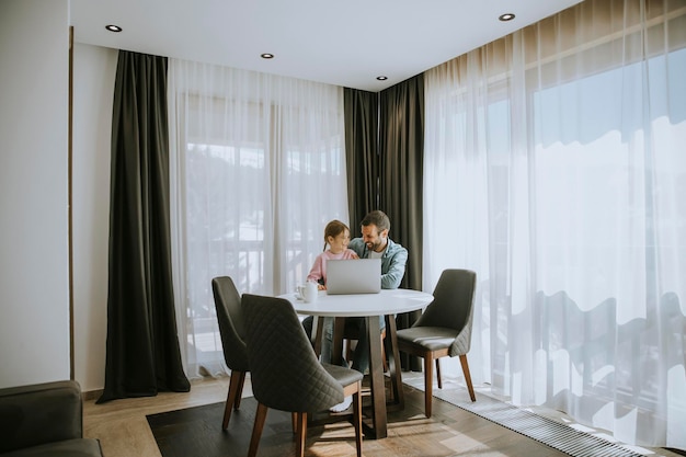 Father and daughter using laptop computer together in the room