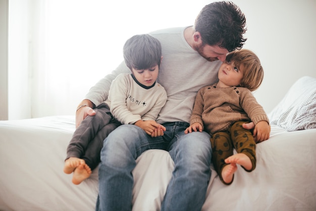 Father embracing toddler sons