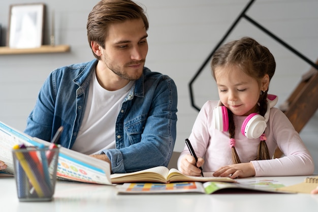 A father helping his little daughter to do her homework for the school.