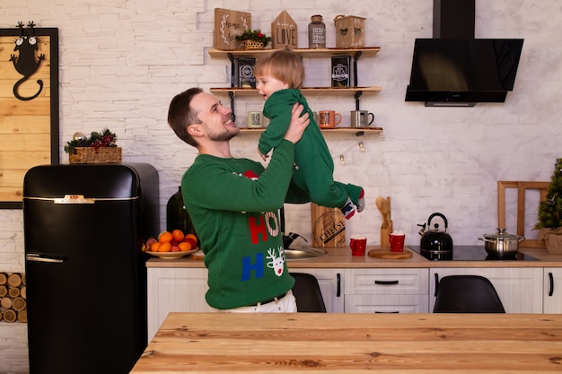 Father higging his child in Christmas kitchen at home.