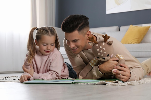 Father and his daughter reading book at home Floor heating concept