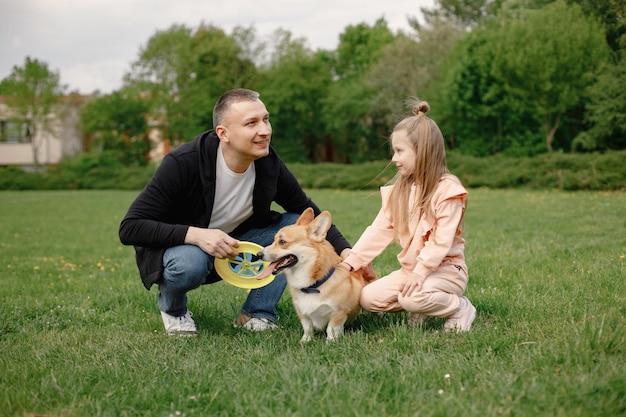 Father his daughter and their corgi dog in playing together in a spring park