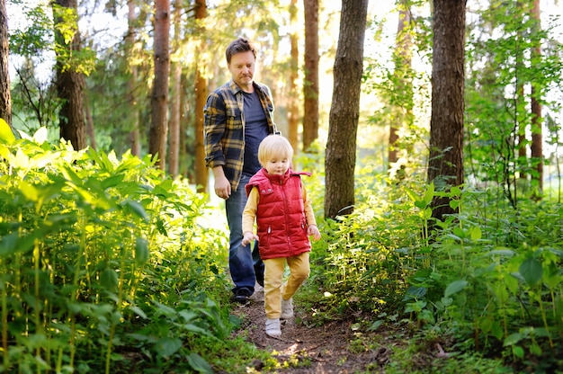 Father and his little son during the hiking activities in forest at sunset