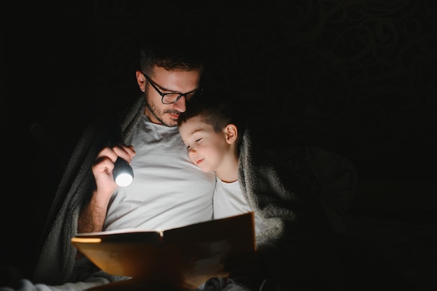 Photo father and his little son reading bedtime story at home