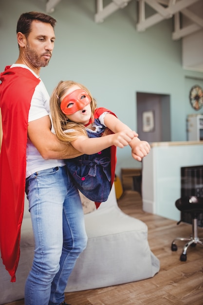 Father holding daughter wearing superhero costume