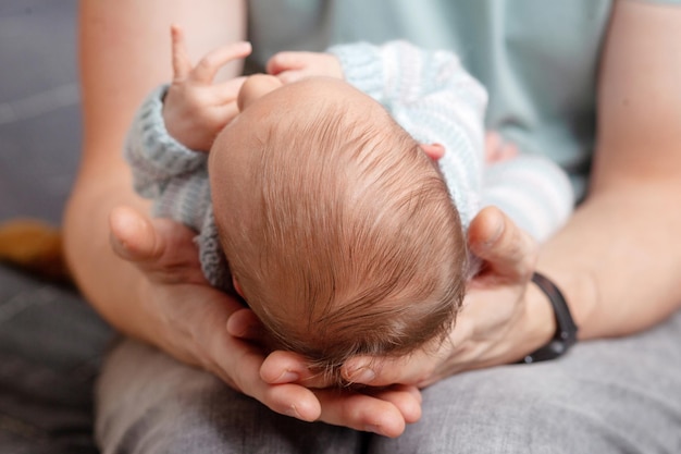 Father holding head of his newborn son in hands The baby on hands at dad Loving parents hand holding cute sleeping newborn baby child