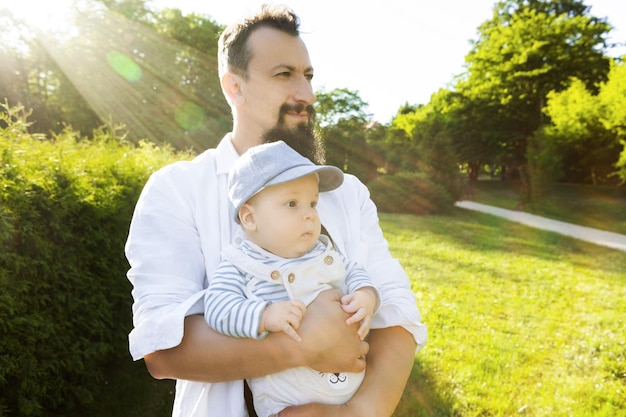 father holding his son in his arms on a background of greenery