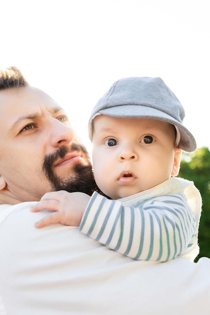 father holding his son in his arms on a background of greenery