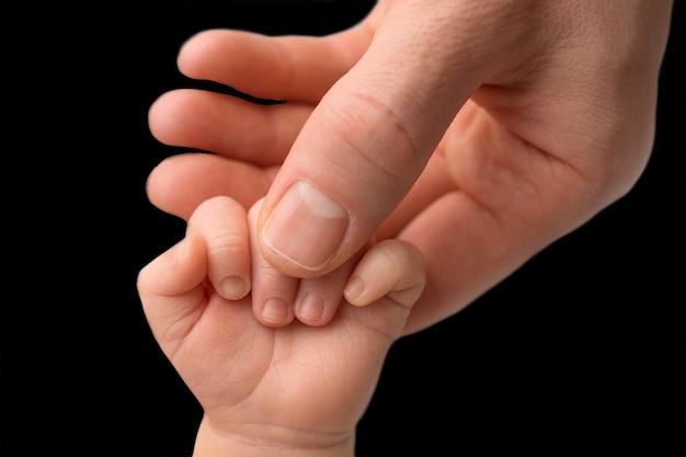 Father holding newborn baby's fingersnewborn . Hand of a newborn baby. Hands of parents and baby close up. Black and white photo. High quality photo