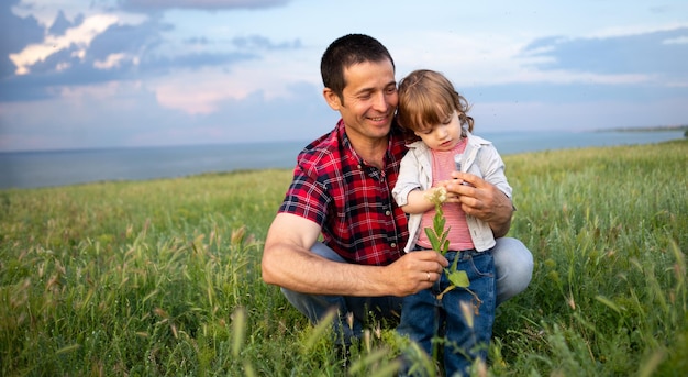 Father holds his little son tightly while walking in the evening at sunset Happy family dad and son on the blue sky background field Time together