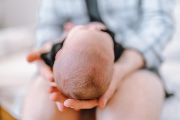 The father holds the newborn on his lap with his head to the camera Focus on the child's head