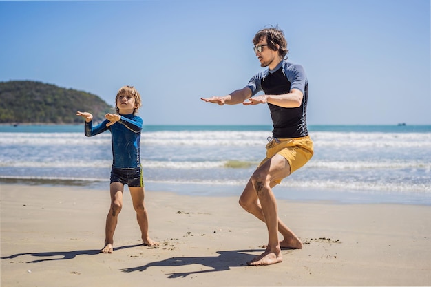 Father or instructor teaching his son how to surf in the sea on vacation or holiday travel and