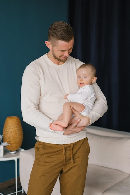 The father is holding a baby in his arms Both are dressed in casual clothes Family Father's Day