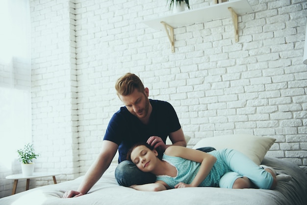 Father is stroking hair of daughter, girl is sleeping.