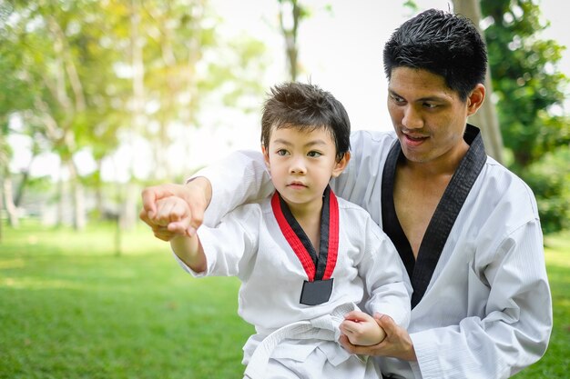 Father is Teacher teaching taekwondo kids, children boy are learning in the nature