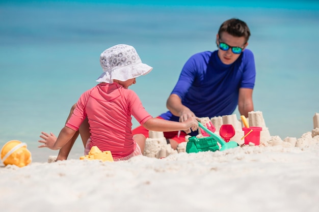 Father and kid making sand castle at tropical beach family playing with beach toys