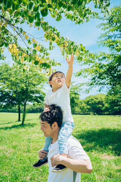 A father and a little boy walking on the green space with piggybacks