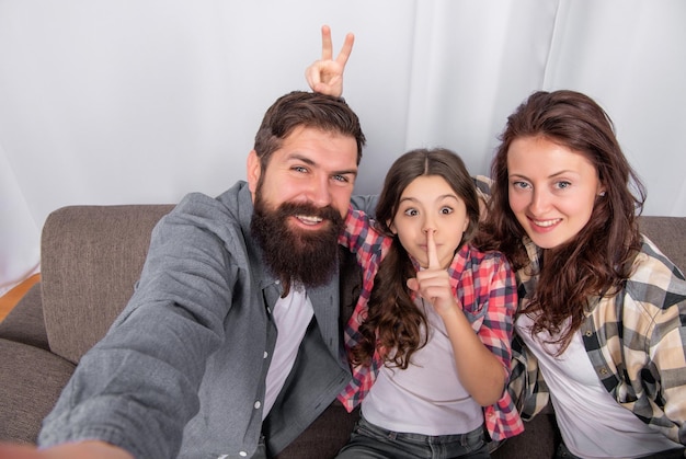 Father mother and child on sofa friendly family having fun positive funny parents with kid