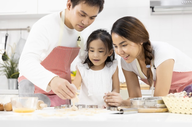 Father, mother and daughter are preparing cookies in the kitchen