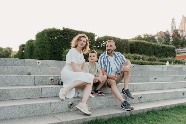 Father mother and son are sitting on the steps in the garden of an old town