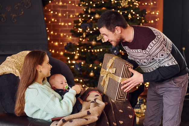 Father and mother with their child together in christmas decorated room.