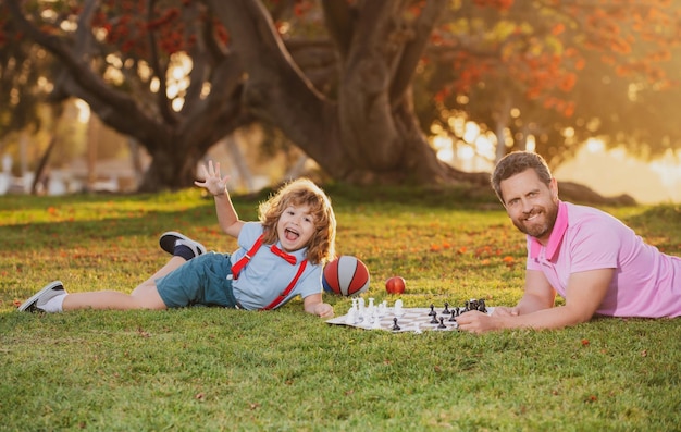 Father play chess with son family outside game child learning to play chess little boy think or plan