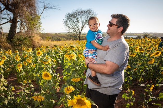 Father playing with adopted son in the sunflowers field.