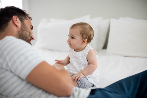 Father playing with his baby girl in bedroom at home