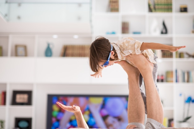 Father playing with his little son on sofa at home