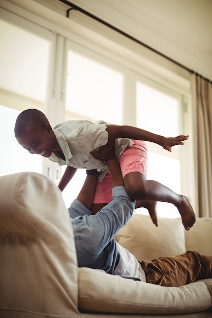 Father playing with son on sofa in living room