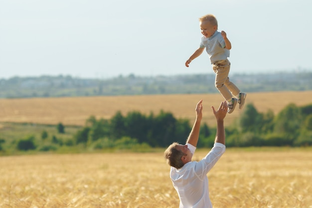 Father playing with son on summer weadow