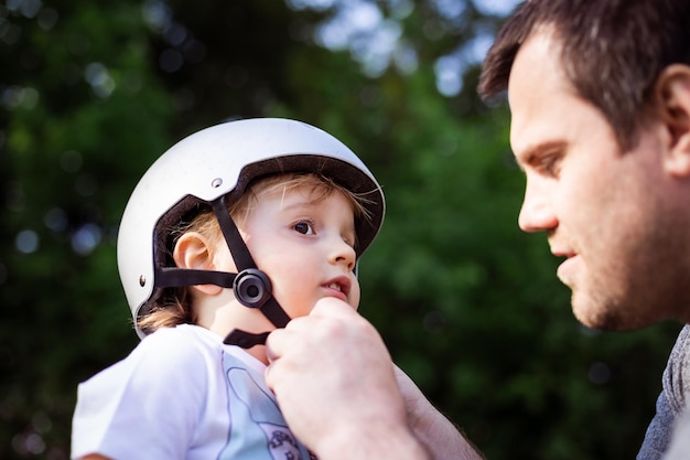 Father putting on his toddler son protective helmet family activities outdoor Child safety