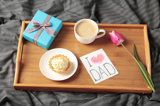 Father's day concept with gift and breakfast on tray Breakfast for dad with croissant and coffee