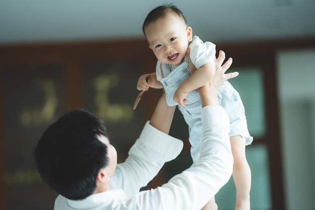 Father's Day concept young Asian father holding a baby child with family person at home happy childhood with love and care together little cute son with dad and parent parenthood lifestyle