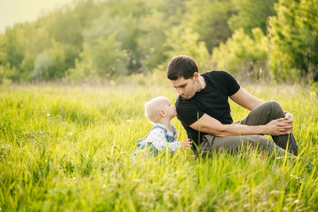 Father's day. A man and his daughter enjoy a vacation in a green park or forest in the warm rays of the sun, experiencing family joy.