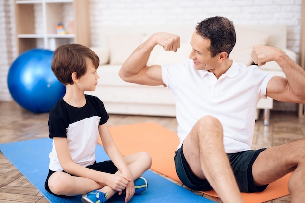 The father shows his son his muscles.