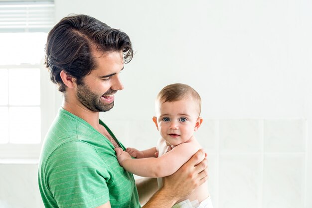 Father smiling while carrying son at home