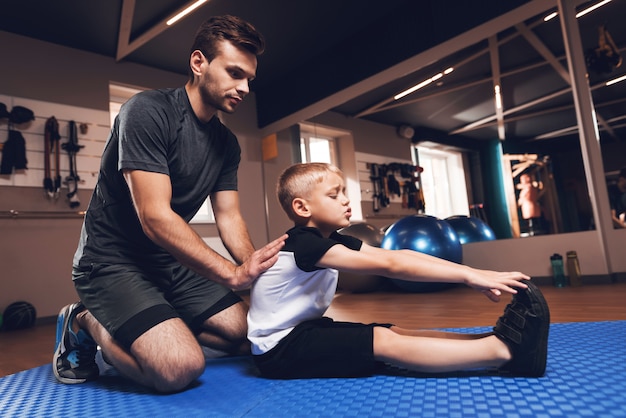 Father And Son Are Stretching Each Other In Gym.