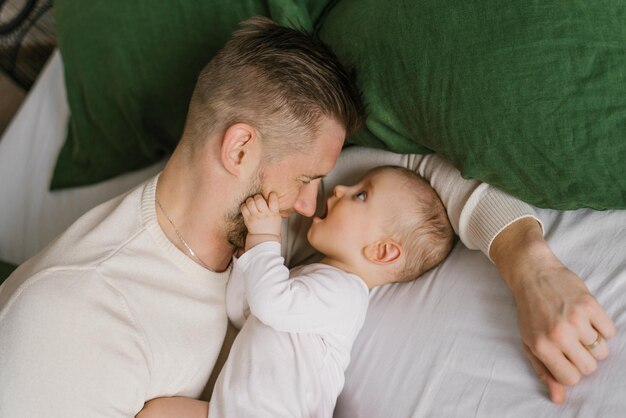 Father and son baby are lying on the bed and having fun