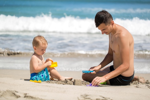 Father and son building sand castle on beach