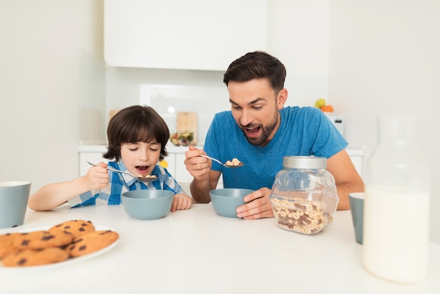 Father and son have breakfast in the light kitchen.