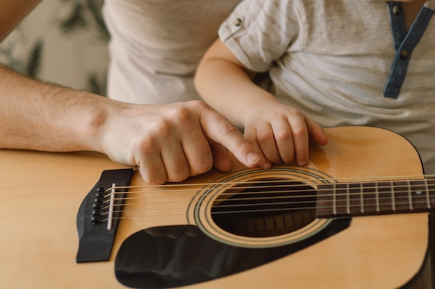 Father and son learning how to play acoustic guitar.