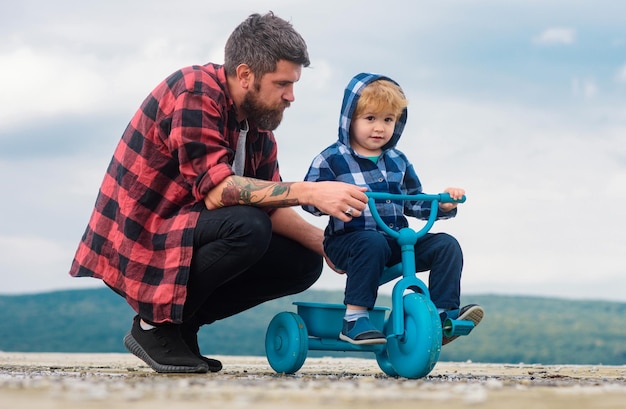 Photo father and son learning to ride a bicycle little boy learn to ride a bike with his daddy dad teaching child boy to ride bicycle