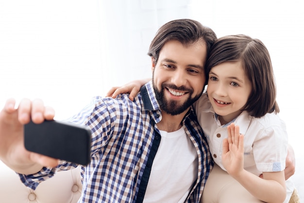 Father and son make selfie on phone at home.