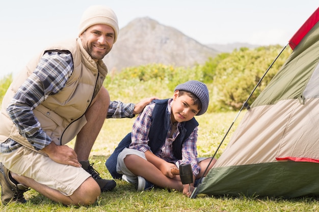 Father and son pitching their tent