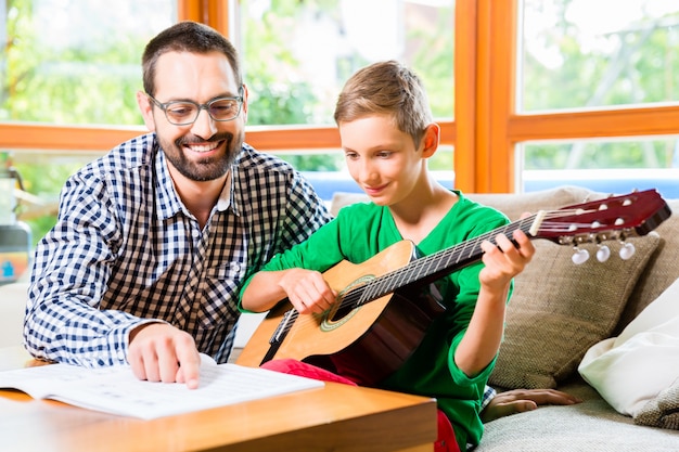 Father and son playing guitar at home