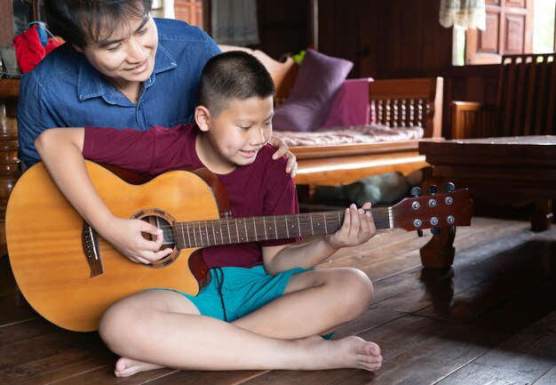 father and son playing guitar together father teaching son how to play guitar