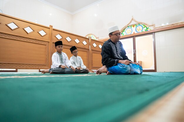 Photo father and son praying together in the mosque