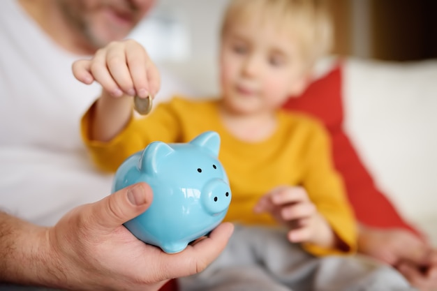 Father and son putting coin into piggy bank