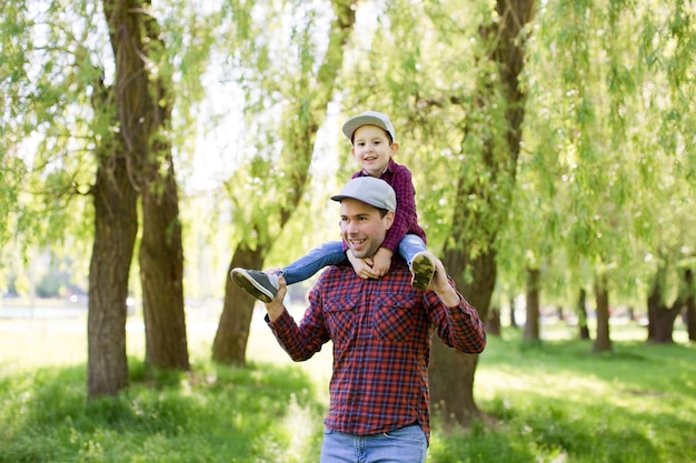 Father and son in red shirts walk in the spring park Happy fathers day concept